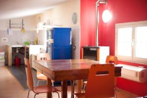 uma cozinha com uma mesa e cadeiras de madeira e um frigorífico azul em Loft mansardato con giardino e piscina in villa privata Loft with garden and swimming pool in a private villa em Sestu