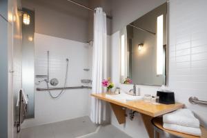 a bathroom with a sink, toilet, and mirror at Canvas Hotel Dallas in Dallas