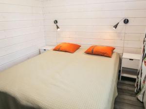 a bedroom with a bed with two orange pillows on it at Holiday Home Villa vuosseli b 1 by Interhome in Ruka