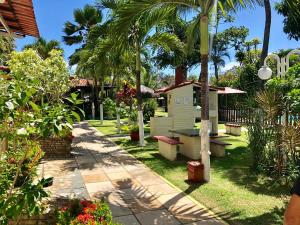 a garden with palm trees and a table and benches at Pousada Portuguesa in Natal