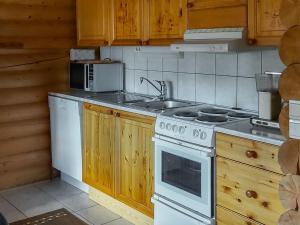 Il comprend une cuisine équipée d'une cuisinière blanche et d'un évier. dans l'établissement Holiday Home Harjurinne by Interhome, à Kinnula