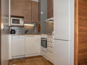 uma cozinha com electrodomésticos brancos e armários de madeira em Holiday Home Ylläs chalets a307 by Interhome em Ylläs