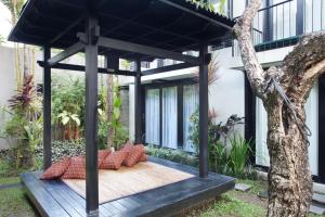 a pergola on a deck in front of a house at S'cape Condotel in Sanur