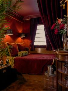 a bedroom with a bed with red walls and a window at House of Gods Royal Mile in Edinburgh