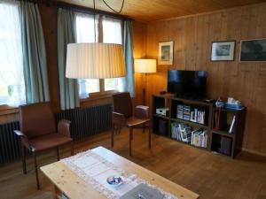 ein Wohnzimmer mit einem TV, einem Tisch und Stühlen in der Unterkunft Apartment Lena- Chalet by Interhome in Gstaad