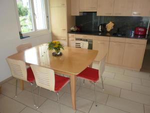 eine Küche mit einem Holztisch und weißen Stühlen in der Unterkunft Apartment Blumenweg 10 by Interhome in Engelberg