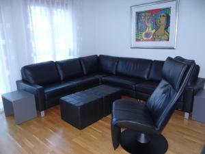 a living room with a black leather couch and a chair at Apartment Dorfstrasse 7-42 by Interhome in Engelberg