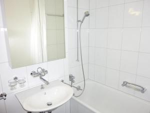 La salle de bains blanche est pourvue d'un lavabo et d'une douche. dans l'établissement Apartment Parkweg 9-102 by Interhome, à Engelberg