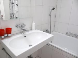 ein weißes Badezimmer mit einem Waschbecken und einer Badewanne in der Unterkunft Apartment Alte Gasse 9 by Interhome in Engelberg