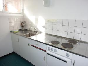 een witte keuken met een fornuis en een wastafel bij Apartment Parkweg 9-207 by Interhome in Engelberg