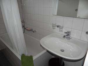 a bathroom with a sink and a mirror and a tub at Apartment Parkweg 9-207 by Interhome in Engelberg