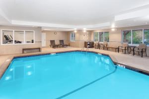 uma piscina num quarto de hotel com cadeiras e mesas em Holiday Inn Express Hotel & Suites Hampton South-Seabrook, an IHG Hotel em Seabrook