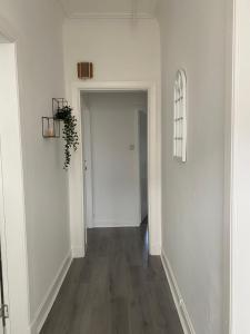 um corredor vazio com paredes brancas e pisos de madeira em Union Street Apartment em Hawick