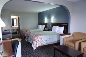 a hotel room with two beds and a chair at Gateway Inn in Clarksville