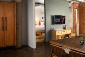 a living room with a television and a bed at Canvas Hotel Dallas in Dallas