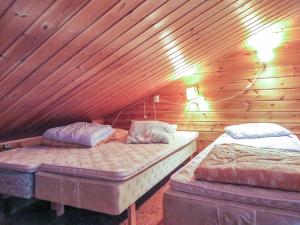 two beds in a room with wooden walls at Holiday Home Lupposyöte b1 by Interhome in Syöte