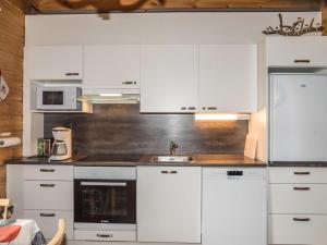 une cuisine avec des armoires blanches et un évier dans l'établissement Holiday Home Lähikaltio 316 by Interhome, à Äkäslompolo