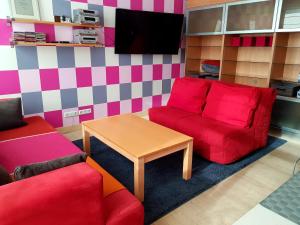 uma sala de estar com um sofá vermelho e uma mesa em Fuksija House em Daugavpils