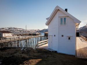 a small white building on a dock next to the water at Lovisenborg Brygge in Kongsfjord