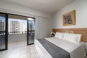 a bedroom with a large bed and a large window at Lumar Hotel in Florianópolis