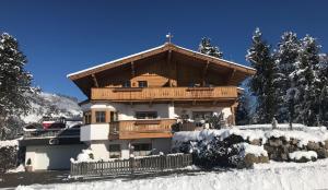 a large wooden house with a balcony in the snow at Appartement Margaretha in Westendorf