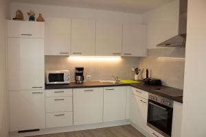 a white kitchen with white cabinets and a microwave at Ernas Ferienhaus in Aschbach bei Fürstenfeld