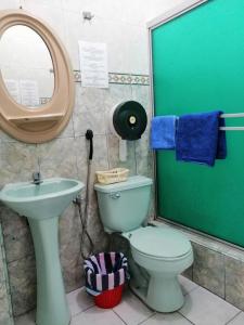 een badkamer met een toilet, een wastafel en een spiegel bij Hotel Pacífico in Guayaquil