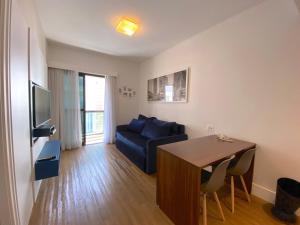 Apartamento conforto - Itaim Bibi في ساو باولو: غرفة معيشة مع أريكة زرقاء وطاولة