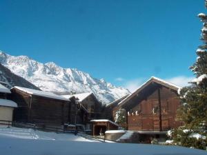 a ski lodge with snow covered mountains in the background at Apartment Haus Alpenrose by Interhome in Saas-Almagell