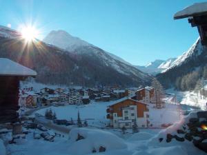 a village in the snow with the sun in the background at Apartment Haus Alpenrose by Interhome in Saas-Almagell