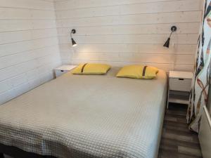 Bett in einem kleinen Zimmer mit zwei gelben Kissen in der Unterkunft Holiday Home Villa vuosseli c 1 by Interhome in Aikkila