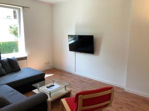 a living room with a couch and a tv on the wall at Ruhige EG Wohnung bei der Burg in Kröllwitz