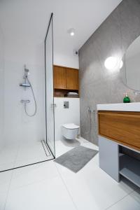 uma casa de banho com um chuveiro, um lavatório e um WC. em City Lights Apartments em Cracóvia