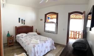a bedroom with a bed and a chair and a window at Viva Brasil Pousada in Paraty