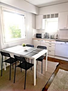 uma cozinha branca com uma mesa e cadeiras brancas em Kuusamon Helmi, Sauna, Parveke, Terassi em Kuusamo