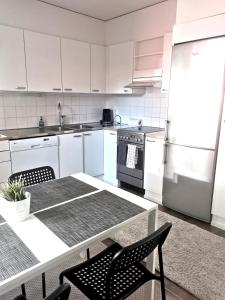 una cocina con electrodomésticos blancos, mesa y sillas en Kuusamon Helmi, Sauna, Parveke, Terassi, en Kuusamo