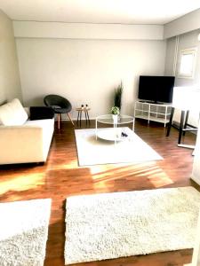 uma sala de estar com um sofá branco e uma televisão em Kuusamon Helmi, Sauna, Parveke, Terassi em Kuusamo