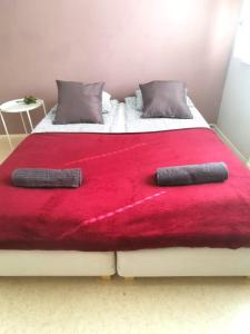 1 cama con manta roja y 2 almohadas en Kuusamon Helmi, Sauna, Parveke, Terassi, en Kuusamo