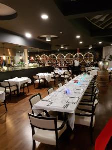 uma grande sala de jantar com mesas e cadeiras brancas em Hotel AL Mulino em Maasmechelen