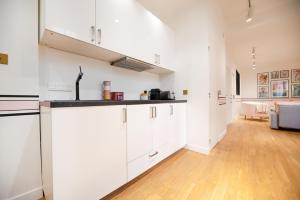 a kitchen with white cabinets and a living room at Dreamyflat - Charonne in Paris