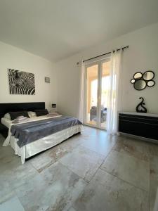 a white bedroom with a bed and a large window at casa muriel in Vescovato
