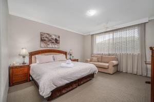 a bedroom with a large bed and a couch at Cotswold Gardens in Armidale
