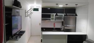 cocina con armarios blancos y negros y nevera en WB Apto condomínio Jubiabá, en Olivença