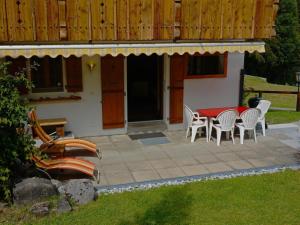 a patio with a table and chairs in front of a house at Apartment Zapfe - Küenzi by Interhome in Saanenmöser