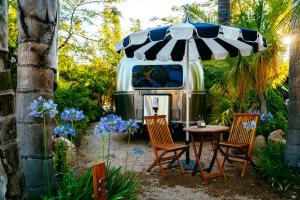 einen Wohnwagen mit zwei Stühlen und einem Tisch mit einem Sonnenschirm in der Unterkunft Caravan Outpost in Ojai