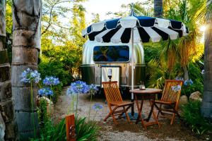 an rv with two chairs and a table with an umbrella at Caravan Outpost in Ojai