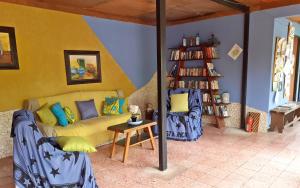 a living room with a yellow couch and a book shelf at Montaña Linda Guest House Orosi in Orosí