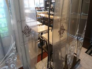 APA Hotel Tokushima Ekimae في توكوشيما: غرفة طعام مع طاولات وكراسي وراء زجاج