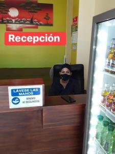 mężczyzna w masce siedzący przy ladzie w sklepie w obiekcie D’ RUIZ HOTEL w mieście Quevedo