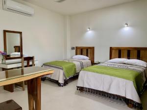 a room with two beds and a desk and a mirror at Lidxi Rosae in Puerto Escondido